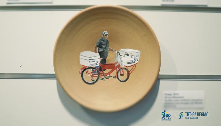 Exposição "Ciclos Urbanos" e uma obra feita em argila, com formato de prato e retrata um homem vendedor de chopp na bicicleta.