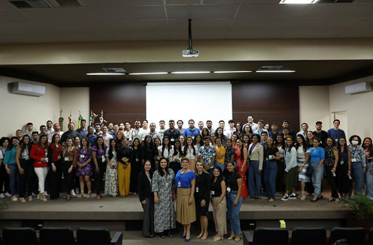 Foto em ambiente fechado, composta com todos os estagiários e estagiárias do tribunal, além de servidores.