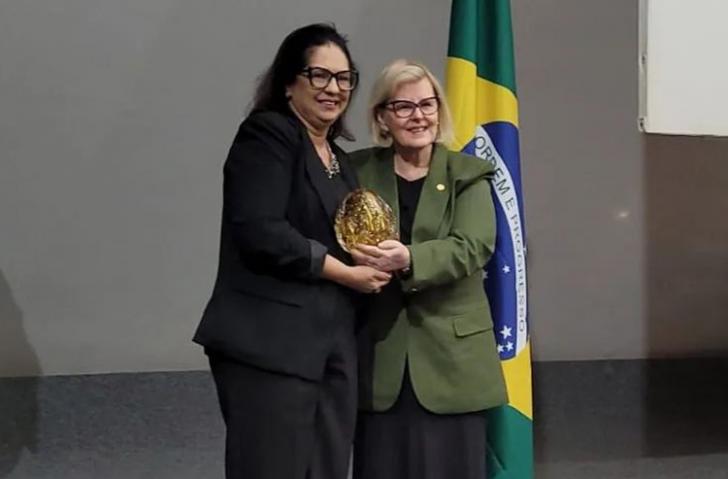 Foto em ambiente fechado. Ao centro, duas mulheres. A direita, a ministra Rosa Weber, do lado esquerdo, a juíza Elinay Almeida.