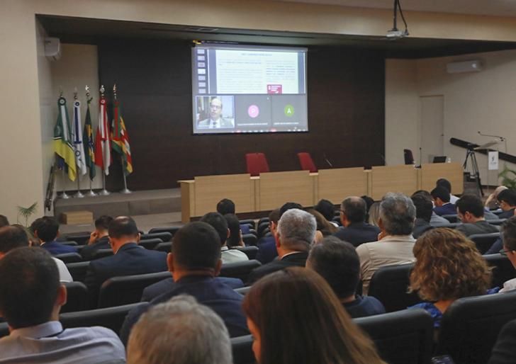 #ParaTodosVerem: Fotografia em ambiente fechado. Contendo dezenas de pessoas sentadas em um auditório.