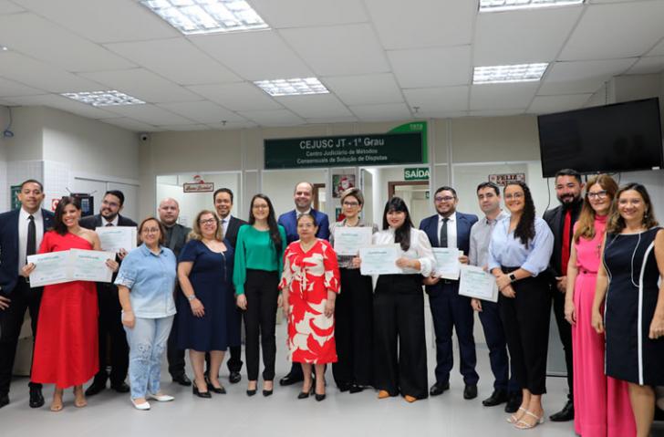 Foto em ambiente fechado com várias pessoas segurando seus certificados.