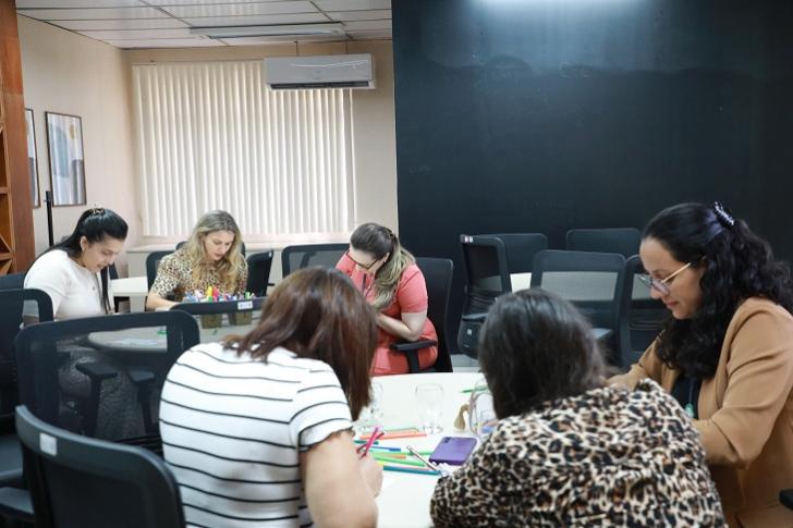 #ParaTodosVerem: Fotografia colorida em ambiente fechado, foto do momento de dinâmica na roda de conversa das participantes.