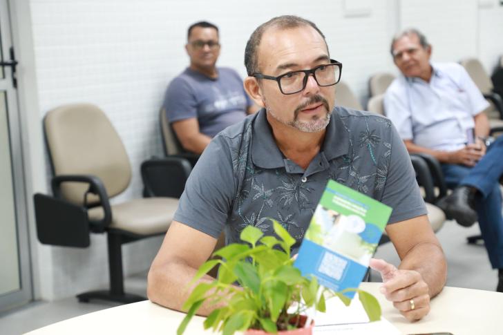 #ParaTodosVerem: Fotografia colorida de um homem branco, ele está sentado e usa óculos de grau.