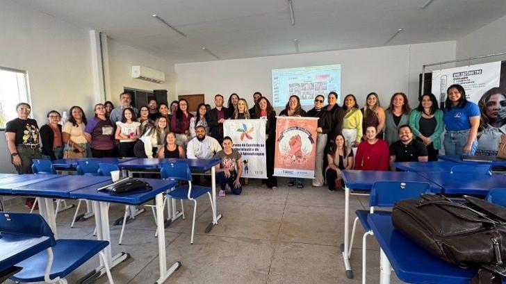 #ParaTodosVerem: Foto colorida em ambiente fechado, reunindo várias pessoas entre homens e mulheres, todos estão em pé sorrindo