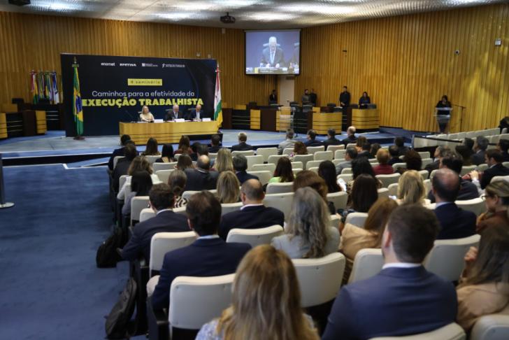 Foto colorida em ambiente fechado, todos as pessoas presentes estão sentadas.