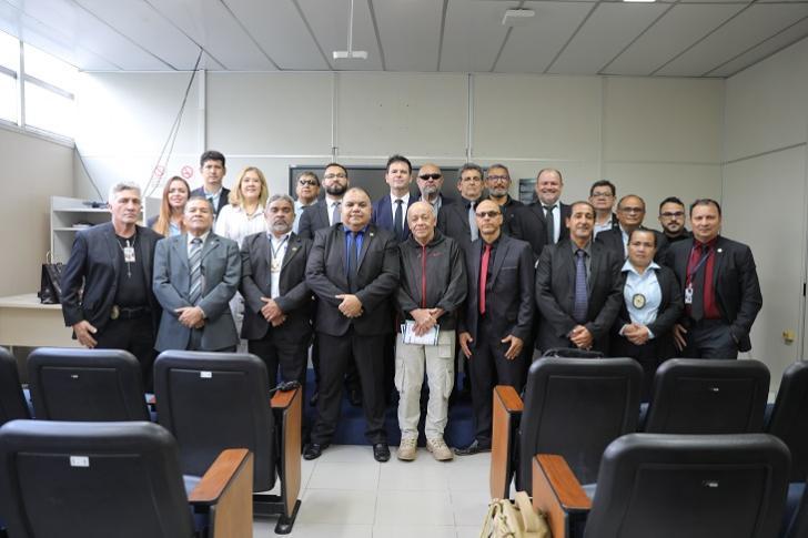 #ParaTodosVerem: Fotografia colorida em ambiente fechado, na foto está reunido diversas pessoas em pé, sorrindo.