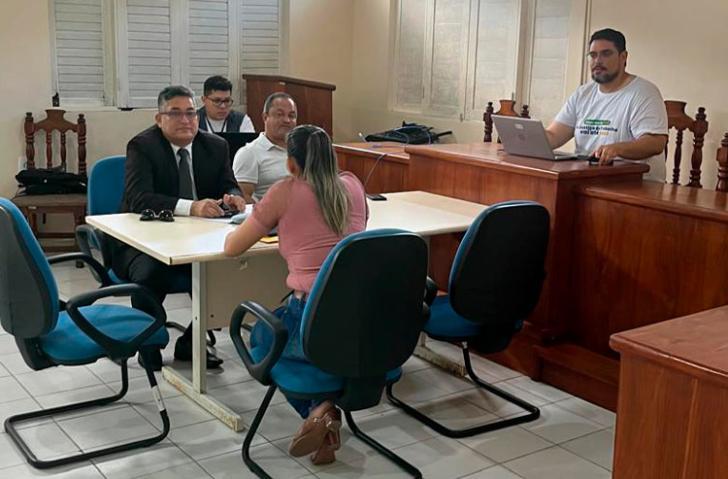Fotografia em ambiente fechado de uma sala de audiência que reúne cinco pessoas,entre homens e mulheres