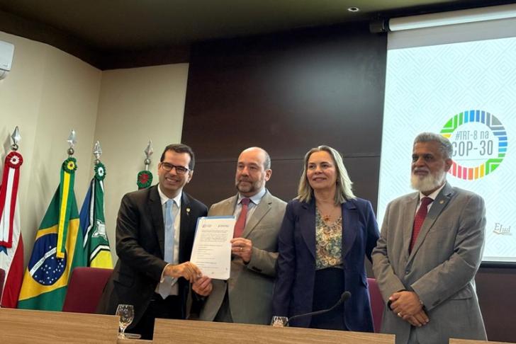 Foto em ambiente fechado mostrando os ministros do TST e o representante da OIT na cerimônia de assinatura do Plano de Trabalho.