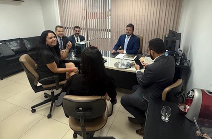 Foto em ambiente fechado mostrando a reunião das autoridades judiciais e representantes da empresa.