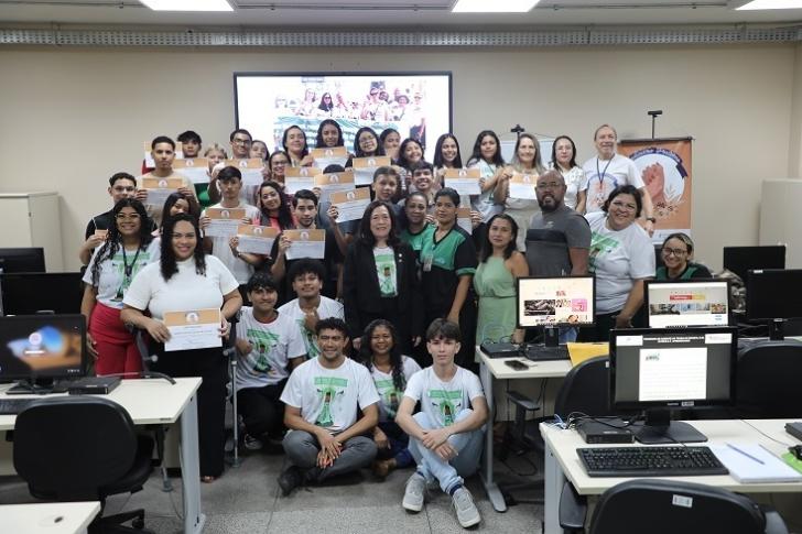 #ParaTodosVerem: Fotografia colorida em ambiente fechado reunindo homens e mulheres, todos estão em pé sorrindo para a foto.
