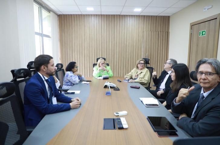 Fotografia em uma sala de reunião, que reúne homens e mulheres
