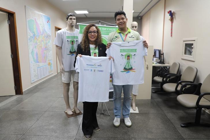 Fotografia de um mulher e um homem, em mãos seguram a camisa da Campanha do Círio 2025