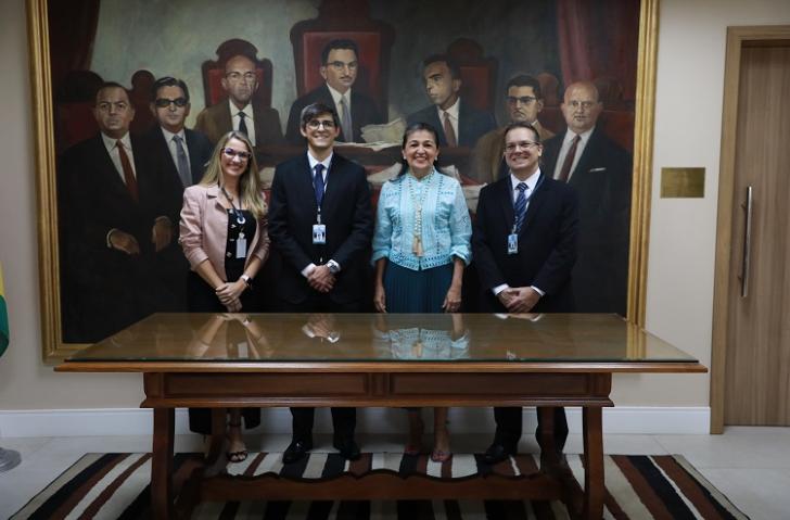 Fotografia em ambiente fechado que reúne quatro pessoas, sendo duas mulheres e dois homens, lado a lado