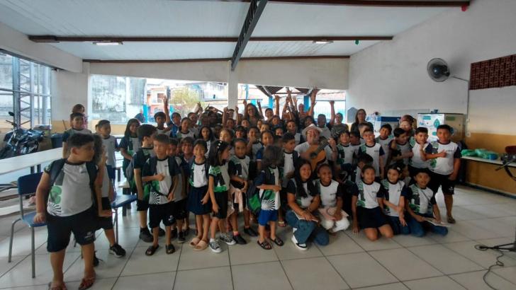 Foto em ambiente fechado com crianças, adolescentes e o músico Salomão Habib