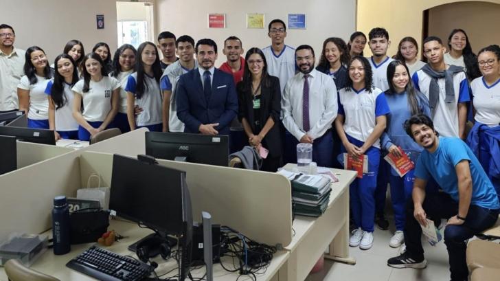 Foto colorida em ambiente fechado do juiz junto com os estudantes