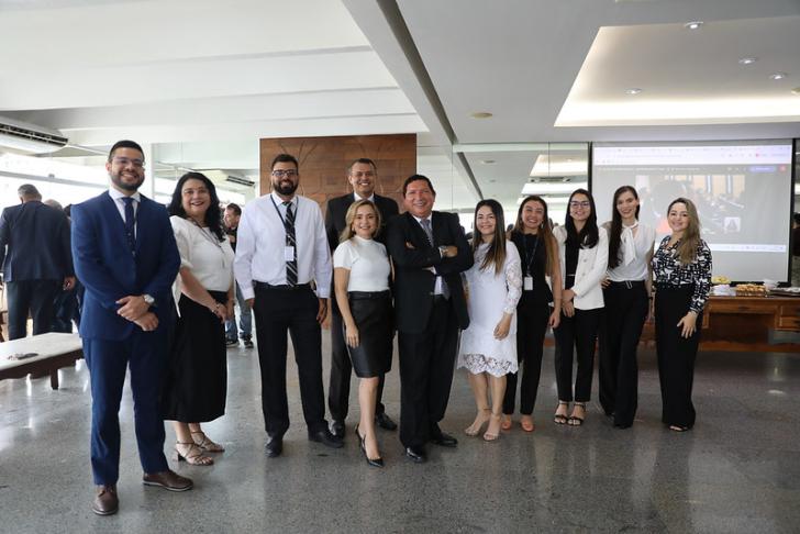 #ParaTodosVerem: Foto em espaço fechado, com algumas pessoas posando para a foto, entre homens e mulheres.