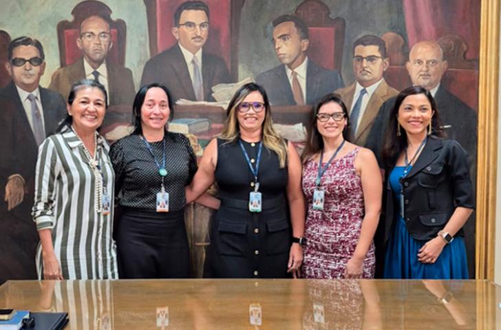Fotografia de cinco mulheres lado a lado, sorrindo