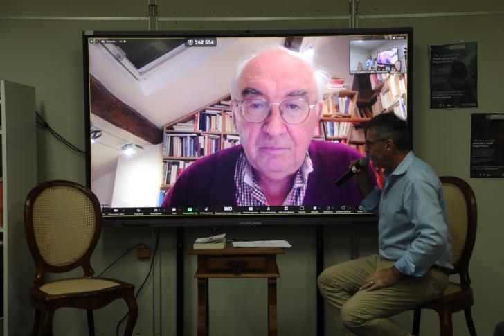 #ParaTodosVerem: Foto em espaço fechado, com o sociólogo Christian Laval em um telão e o professor Jean François Yves Deluchey a