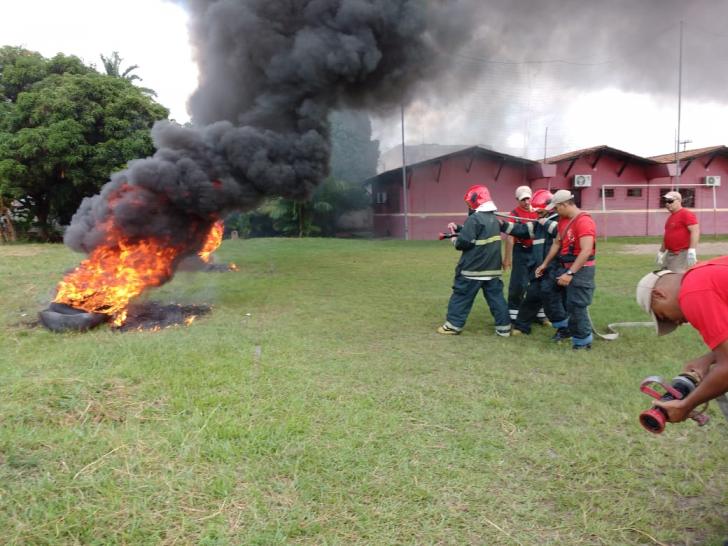 Foto de dois servidores apagando fogo em pneus em um campo aberto.