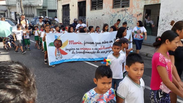 Carregando uma faixa da campanha,meninos e meninas caminham pelas ruas de Belém.