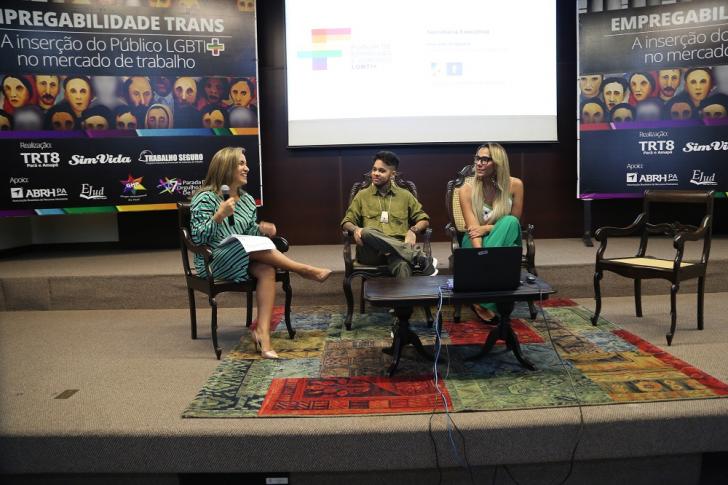 auditório tendo ao fundo banner com identidade visual da campanha empregabilidade trans