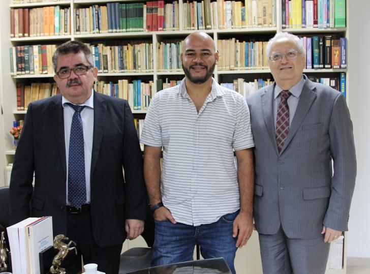 Em pé, na frente de estante de livros,  o Juiz Deodoro Tavares, o professor Magno Braga e o desembargador Vicente Malheiros. 