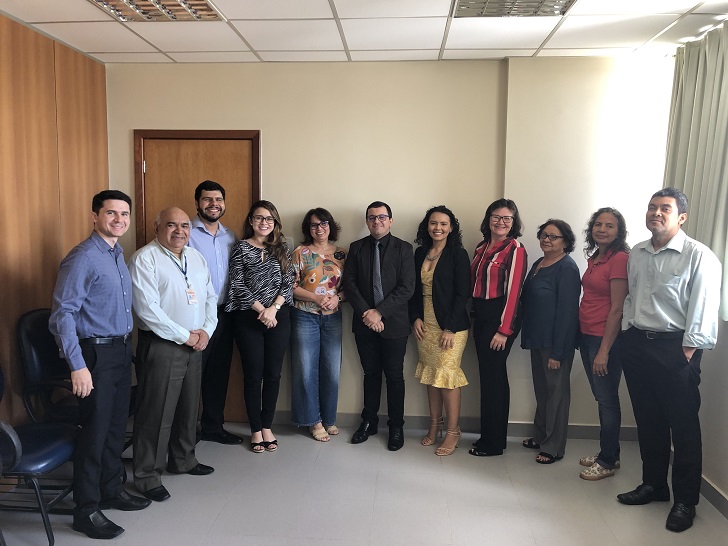 servidores todos em pé ao fundo claro olhando para foto.