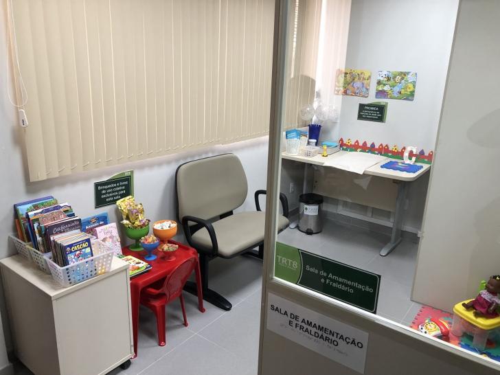 Foto do espaço para amamentação e brinquedoteca contendo livros e brinquedos. 