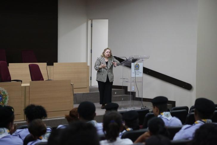 Foto da Desembargadora Sulamir Monassa no auditório falando para estudantes