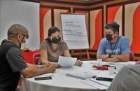 Foto de dois homens e uma mulher sentados a mesa estudando no curso Grid Liderança 