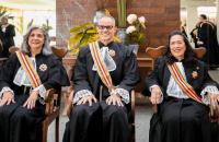 #ParatodosVerem: Fotografia em ambiente fechado, três pessoas sentadas e sorrindo, vestidas com a toga preta e uma faixa nas cor