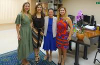 #ParatodosVerem: Fotografia em ambiente fechado. Quatro mulheres brancas lado a lado em uma sala.
