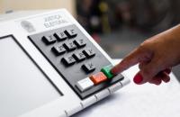 Mão feminina apertado a tecla confirma da urna eletrônica brasileira.