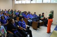 Fotografia em ambiente fechado de um auditório com diversas pessoas sentadas em cadeiras.