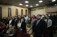 Fotografia em ambiente fechado que reúne dezenas de pessoas em pé 