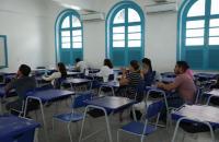 Fotografia em ambiente fechado em uma sala de aula e dezenas pessoas sentadas