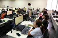 Fotografia em ambiente que reúne jovens, homens e mulheres, no laboratório de informática