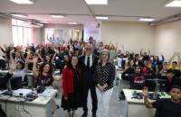 Fotografia em ambiente fechado de diversas pessoas em uma sala de aula.
