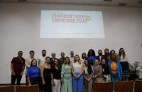 Fotografia em ambiente fechado que reúne homens e mulheres na apresentação do projeto Empregabilidae e Diversidade.