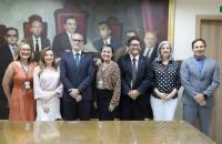 Fotografia em ambiente fechado composta por sete pessoas em pé, lado a lado.