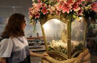 Fotografia em ambiente interno que traz a berlinda com a imagem de Nossa Senhora de Nazaré e uma mulher branca