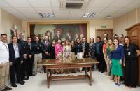 #ParaTodosVerem: Fotografia em ambiente interno, com dezenas de pessoas reunidas em pé sorrindo para a foto. Fim da descrição.