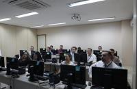 Fotografia em ambiente fechado que reúne 12 pessoas sentadas em um Laboratório de informática, entre homens e mulheres.