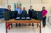 Fotografia em ambiente fechado que reúne cinco pessoas entre homens e mulheres na entrega de equipamentos tecnológicos.