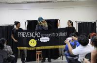  ParaTodosVerem: Fotografia em ambiente fechado, no centro há um homem preto e uma mulher branca vestidos com roupas totalmente 
