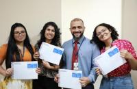 Foto mostra servidores e estagiários da seção psicossocial do TRT-8 posando lado a lado. Eles seguram o planner de saúde mental.