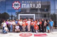 Fotografia em ambiente externo que reúne dezenas de pessoas entre homens e mulheres, lado a lado, em frente o Museu do Marajó