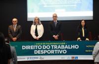Fotografia em ambiente fechado que reúne quatro pessoas em pé, lado a lado, sendo dois homens e duas mulheres