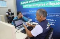 Fotografia em ambiente fechado que mostra dois servidores da Justiça do Trabalho em atendimento. Uma mulher branca que usa óculo