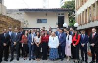 ParaTodosVerem: Fotografia em ambiente aberto, nela, estão homens e mulheres de pé e sorrindo para a foto. 